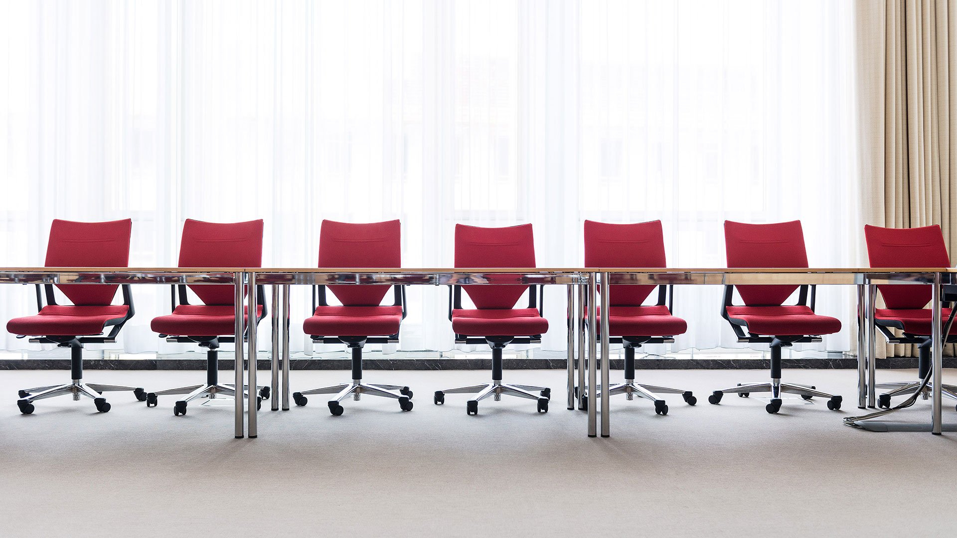 Empty red chairs at a long desk 