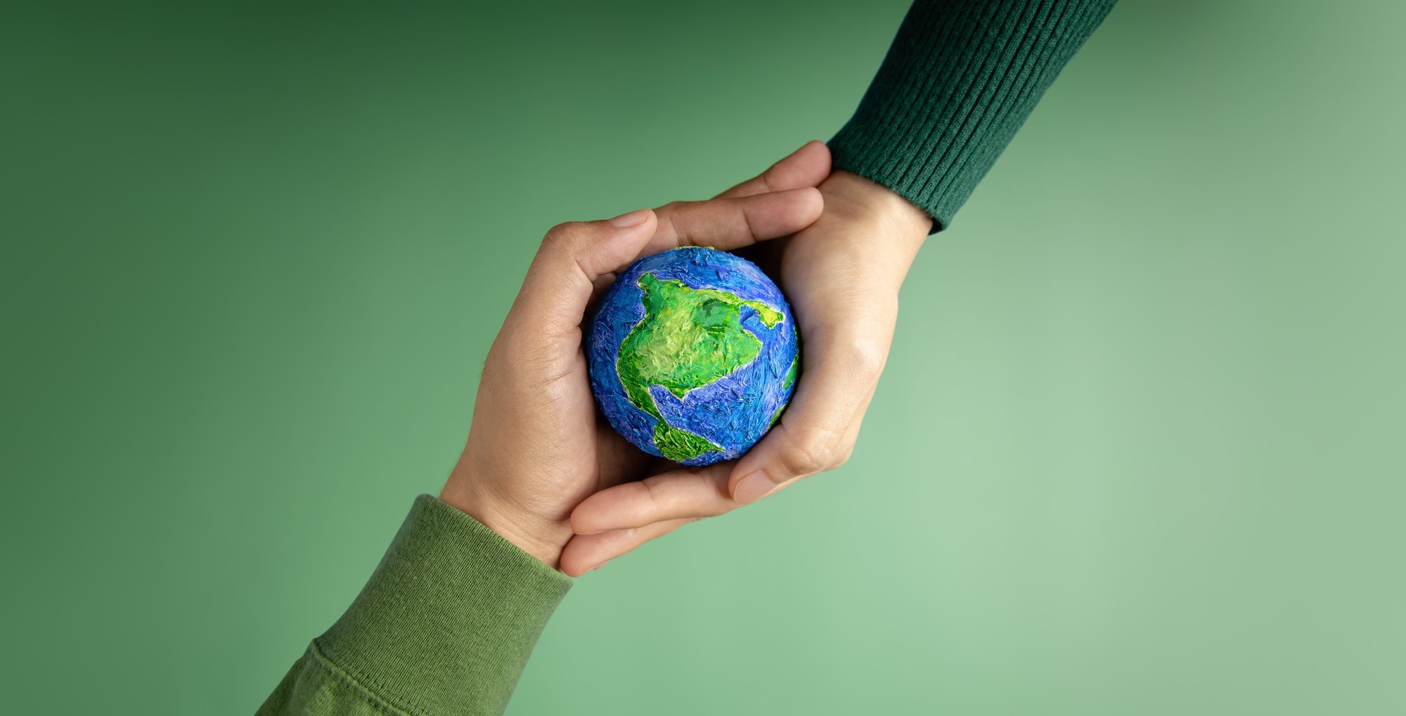 Two hands holding a symbol of the planet Earth.