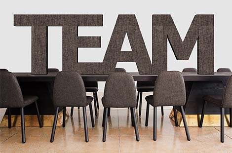 team written in capital letters position on a large table surrounded by chairs