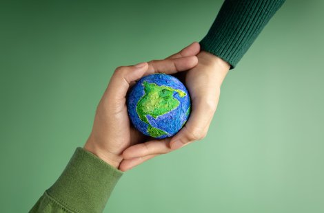 Two hands holding a symbol of the planet Earth.