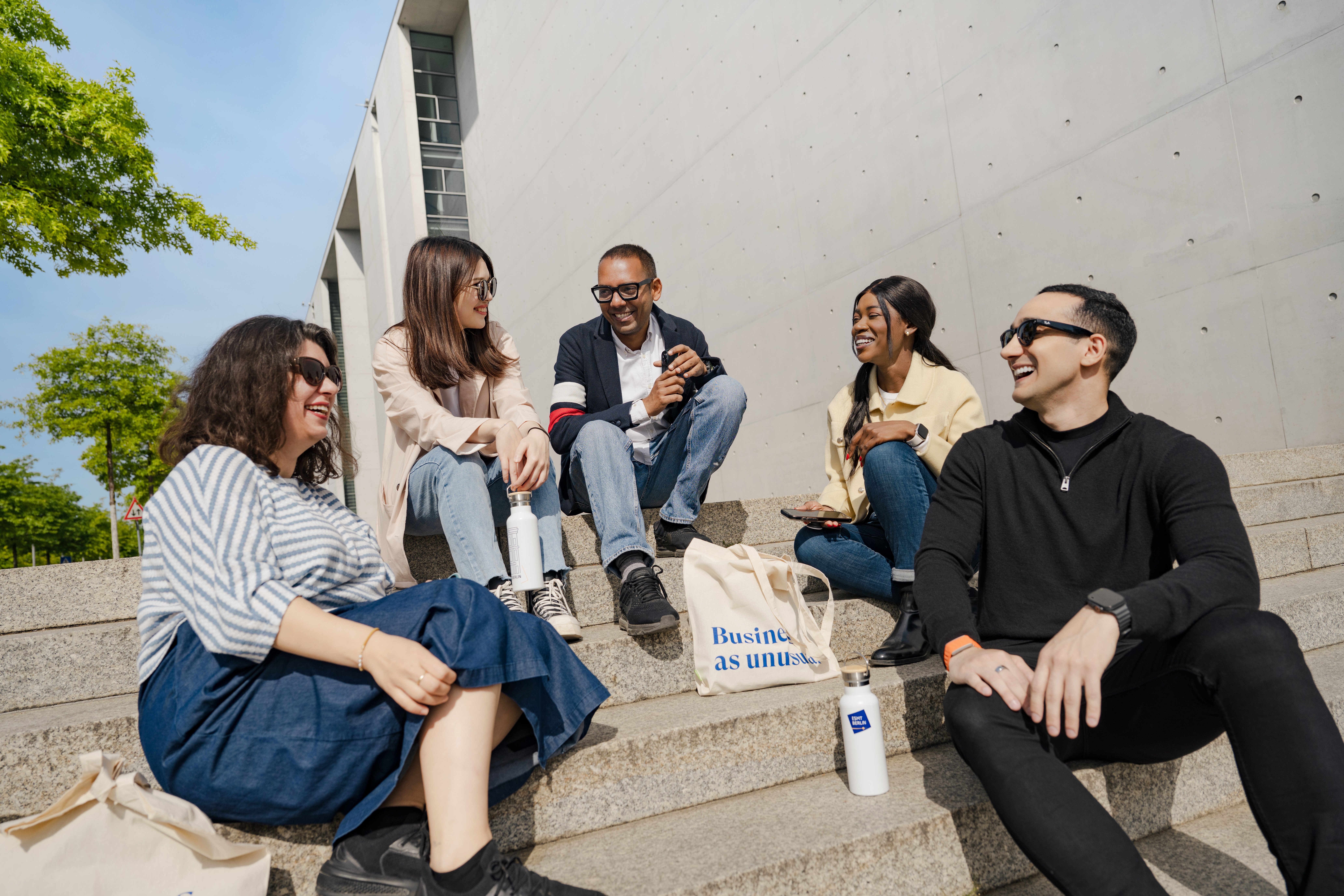 Full-time MBA student Gloria Mopotu and students from ESMT Berlin sitting on stairs 