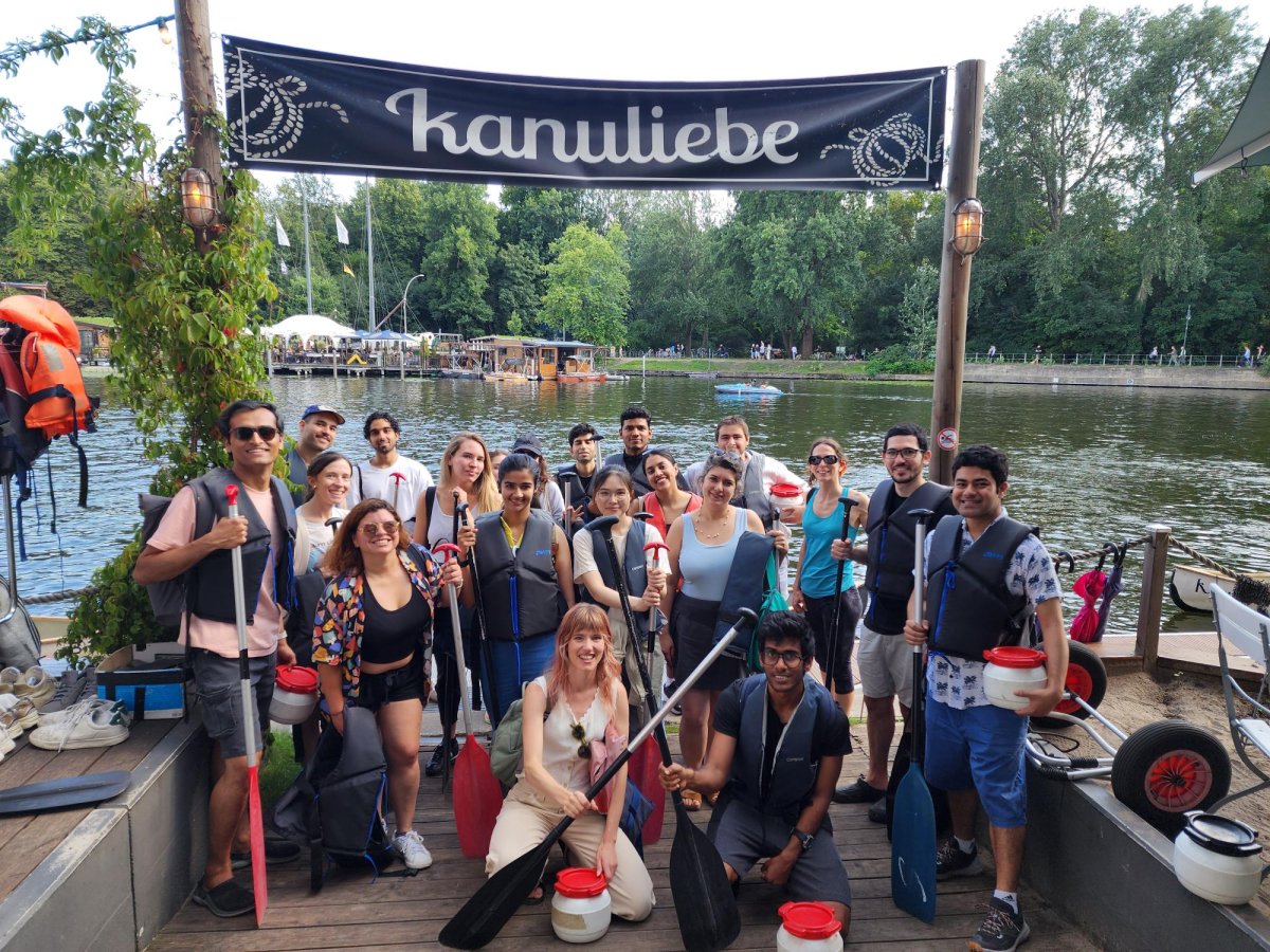 Participants at the ESMT student event Bergfest getting ready for a group canoeing trip. They are standing on a dock in front of boats and smiling.