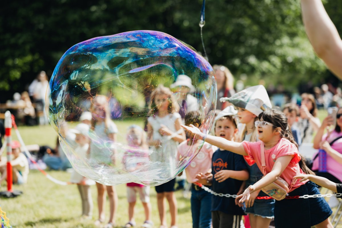 Young guests chase a giant soap bubble during the children's program at "Sommer auf der Insel.