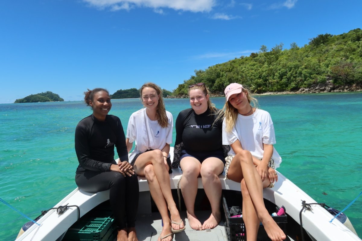 ESMT Berlin Master in Global Management students on a Social Impact Project trip to the Seychelles. They are sitting on a boat in a tropical bay