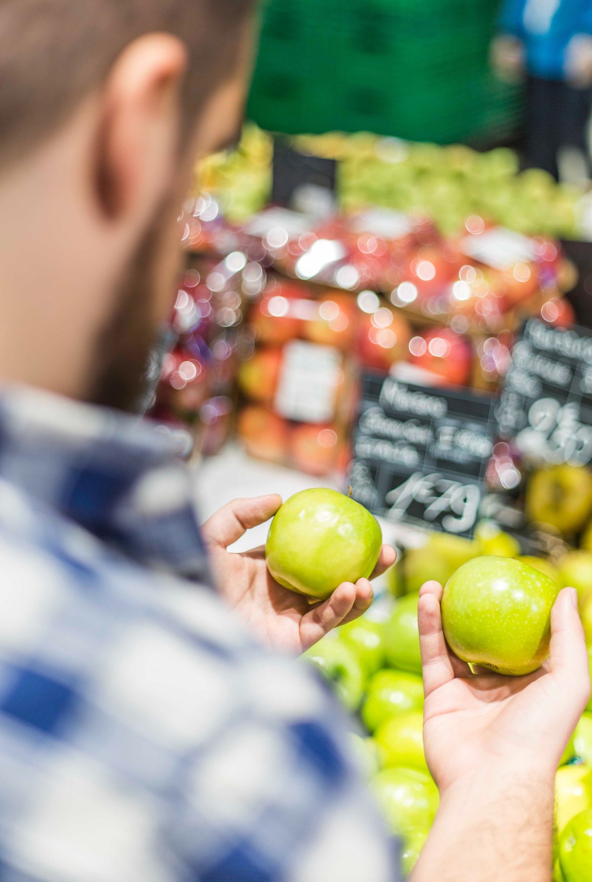 person is examining two apples at a market