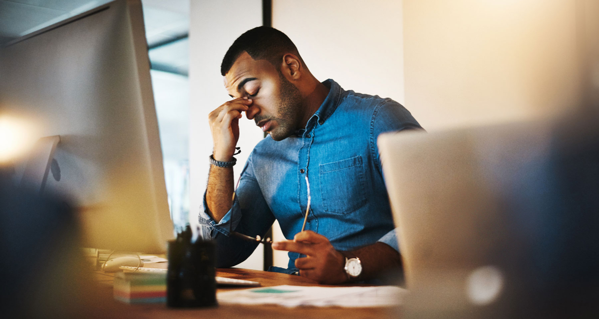 Tired man sitting in front of computer monitor. 