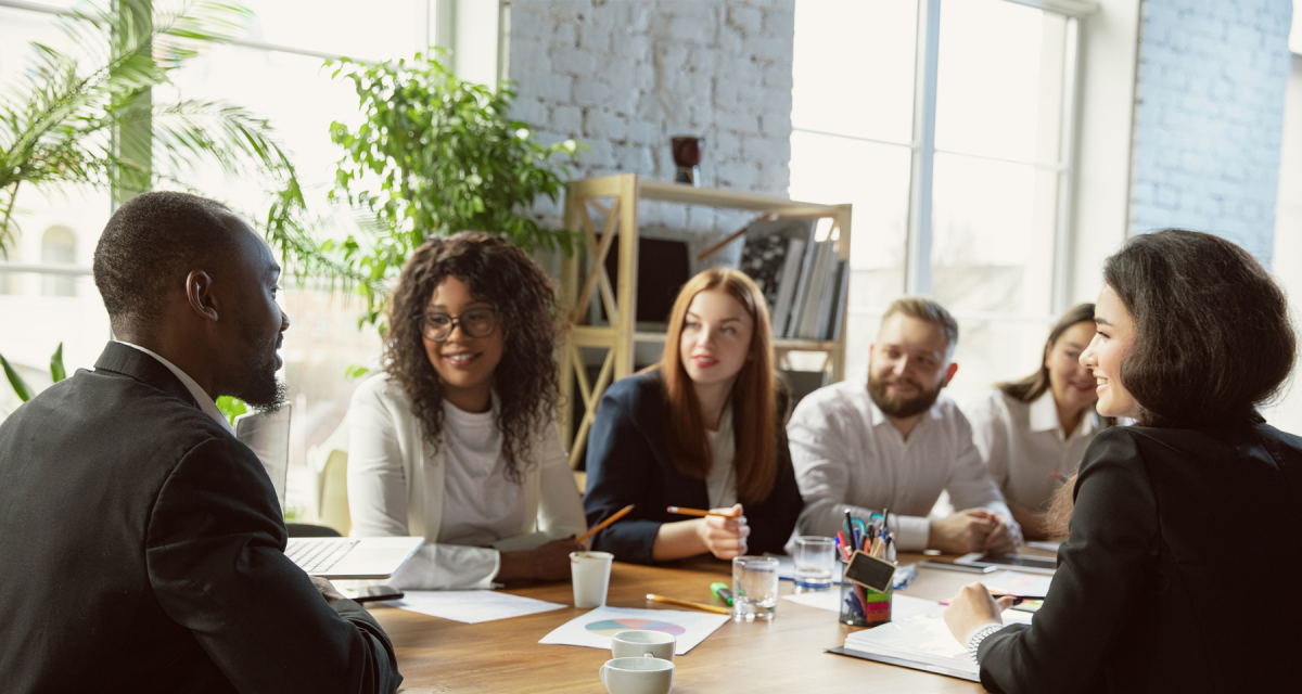 Group of young business professionals having a meeting around a table with papers, pens, notepads