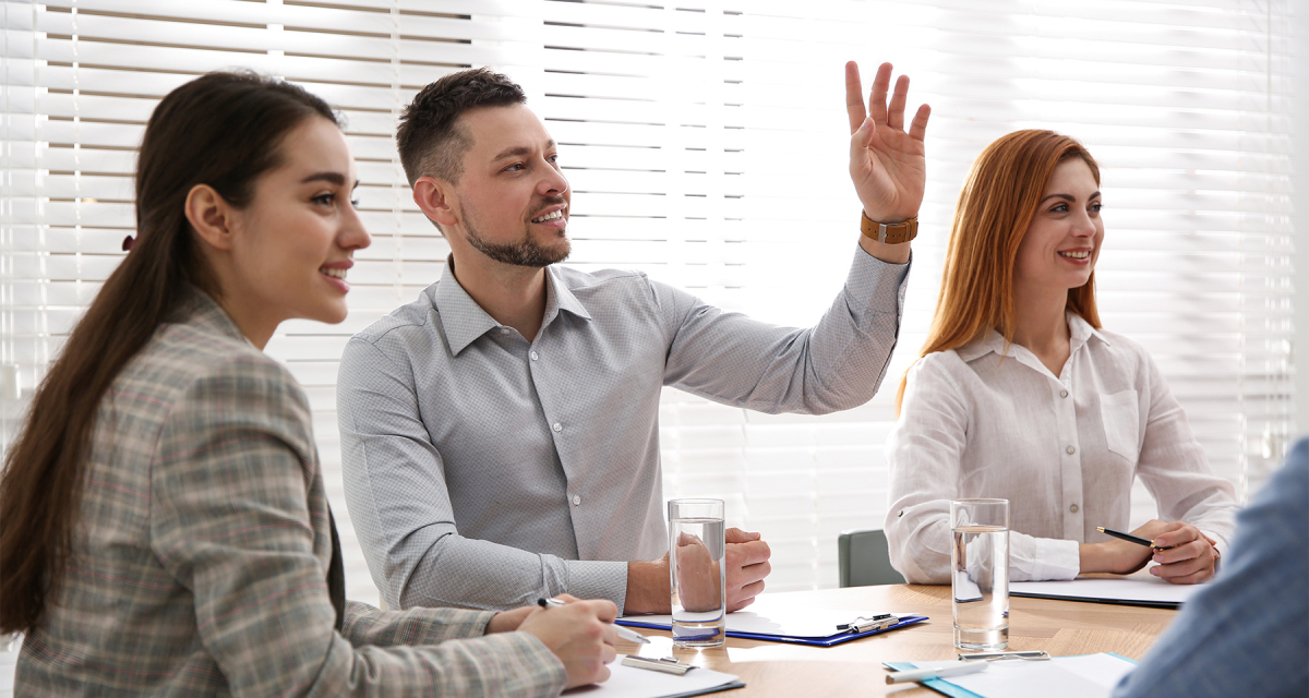 Man raising hand to ask question at business training in conference room