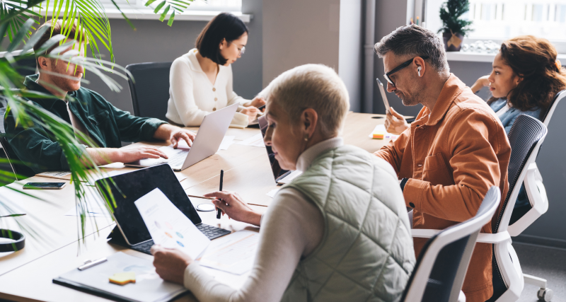 Five people sitting around a desk co-working