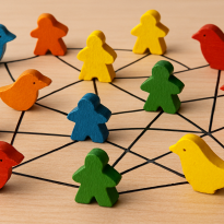 A photograph captures a vibrant network of multicolored wooden birds and meeples, connected by crisp white lines against a neutral beige background. 