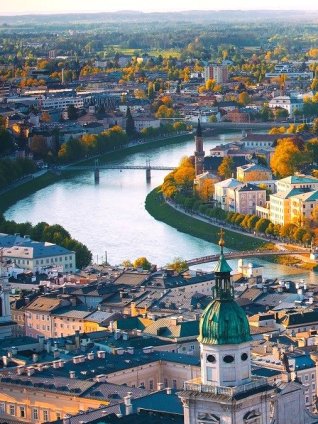 Aerial view of Vienna, showing the Danube alongside domes, bridges, and autumn-colored trees