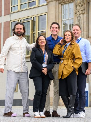 A group of ESMT Berlin Executive MBA participants standing outside the main building on campus and smiling
