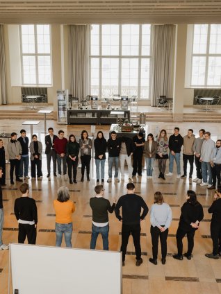 ESMT students taking part in a business-development bootcamp. They are standing in a circle in one of the campus event vestibules