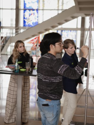 The ESMT Berlin Master in Innovation and Entrepreneurship students working on a group project during the Ideation Bootcamp. You can see the campus stained glass window in the background.