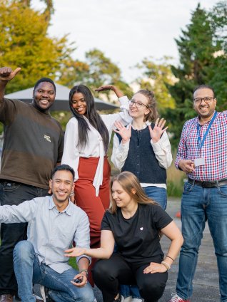 A group of ESMT Berlin Global Online MBA students smiling in the campus garden during Berlin Experience Week