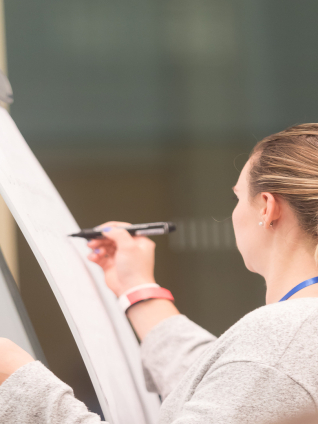 Person writing on flipchart in classroom setting
