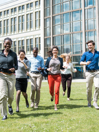 Six students running towards the camra on a green field. 