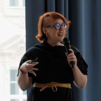 Full-time MBA alum Larissa Reinprecht speaking on stage in front of a crowd at the ESMT Berlin Annual Alumni Meeting