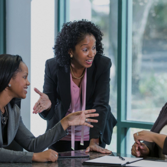Three black business women in a board having a discussion.