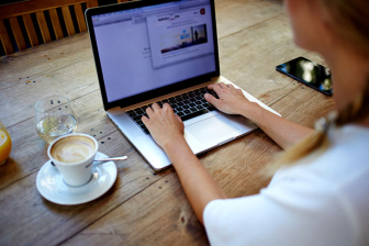 Back view of young successful female freelancer use net-book for distance work during her recreation time, woman's hands keyboarding on portable laptop computer with blank copy space on the screen