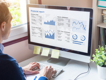 A man looking at a financial report on his computer screen