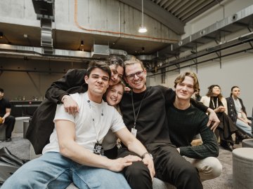 Master's students hugging looking at the camera