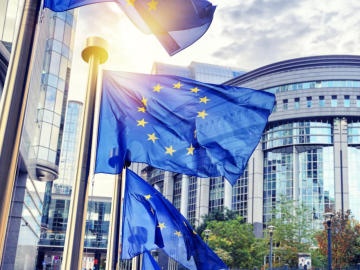 Flags of the European Union flying in front of the European Parliament in Brussels.