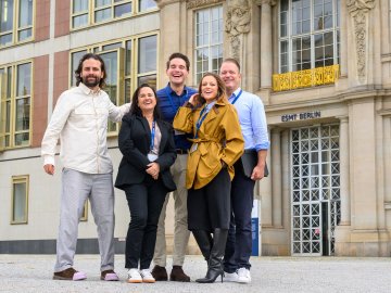 A group of ESMT Berlin Executive MBA participants standing outside the main building on campus and smiling