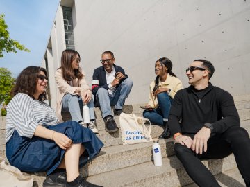 Full-time MBA student Gloria Mopotu and students from ESMT Berlin sitting on stairs 