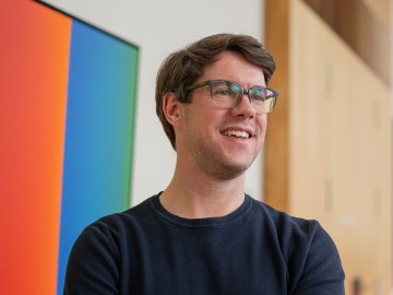 ESMT Part-time MBA student Jan Zimmermann on the Berlin campus, smiling in front of an artwork