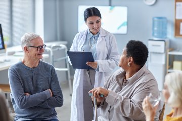 Doctor speaking with a group of older adults during a support group or consultation in a medical office.