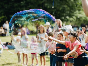 Young guests chase a giant soap bubble during the children's program at "Sommer auf der Insel.