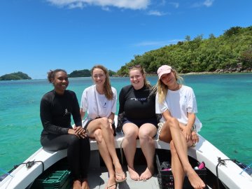 ESMT Berlin Master in Global Management students on a Social Impact Project trip to the Seychelles. They are sitting on a boat in a tropical bay