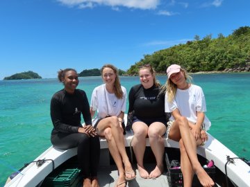 ESMT Berlin Master in Global Management students on a Social Impact Project trip to the Seychelles. They are sitting on a boat in a tropical bay