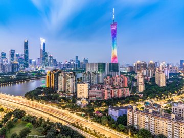 Guangzhou skyline at dusk with rainbow-lit tower, river, and highway light trails