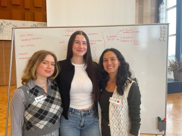 ESMT Berlin Master in Innovation and Entrepreneurship students Jasmin Mantwill, Laura Ruiz, and Gwyneth-Tyger Carys Neumann standing in front of a whiteboard brain-storm while working on their app Lunara