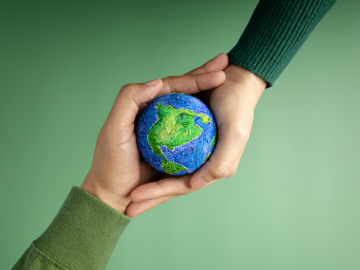 Two hands holding a symbol of the planet Earth.