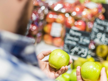 person is examining two apples at a market