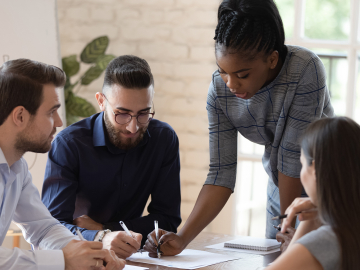 Diverse group of people at an office meeting looking at paper on table