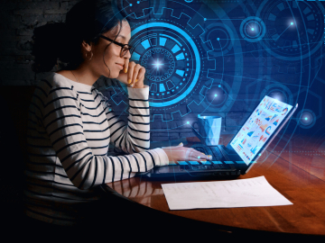 woman sitting at desk working on laptop with digital graphics surrounding her