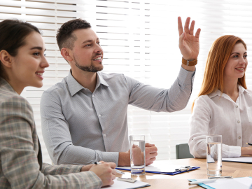 Man raising hand to ask question at business training in conference room