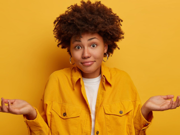 Puzzled African American woman shrugs shoulders and expresses uncertainty
