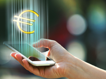 Hand holding a mobile phone with euro sign outdoors, on blurred background