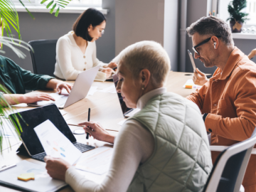 Five people sitting around a desk co-working