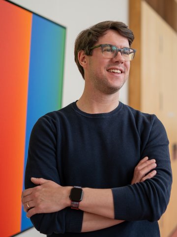 ESMT Part-time MBA student Jan Zimmermann on the Berlin campus, smiling in front of an artwork