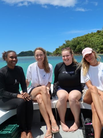 ESMT Berlin Master in Global Management students on a Social Impact Project trip to the Seychelles. They are sitting on a boat in a tropical bay