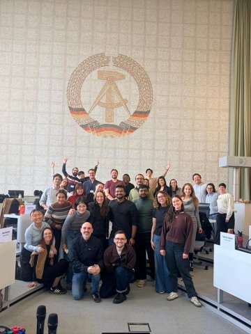 ESMT Full-time MBA students from the Class of 2027 taking a group photo in front of a DDR mosaic in a campus lecture theater