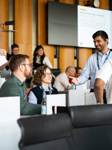 MBA students talking together in a group in an ESMT Berlin auditorium during the annual Berlin Experience Week