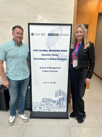 Two ESMT Berlin Executive MBAs from the Class of 2026 on an exchange to Fudan university in Shanghai. They are standing in front of a Fudan sign and smiling.