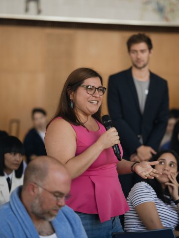 An ESMT Berlin student in a hot pink shirt asking an audience question during a demo day in the Incubation II program on campus